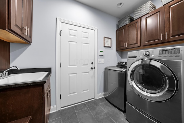 laundry area with washing machine and clothes dryer, cabinet space, a sink, dark tile patterned floors, and baseboards