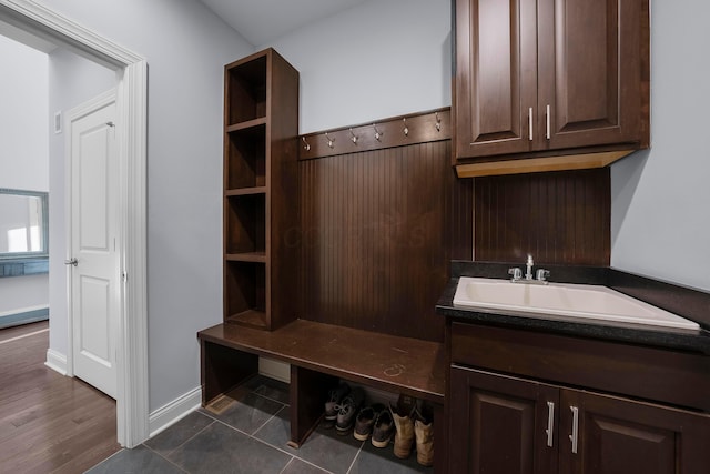 mudroom featuring baseboards, a sink, and dark tile patterned flooring