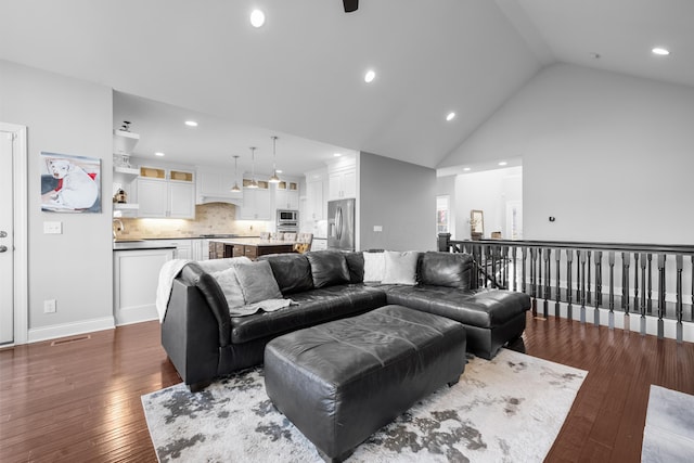 living area with high vaulted ceiling, recessed lighting, visible vents, and dark wood finished floors