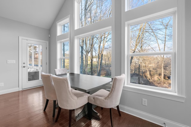 dining area with high vaulted ceiling, baseboards, and wood finished floors