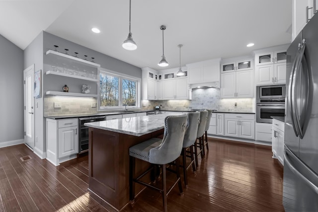 kitchen with dark wood-style floors, white cabinetry, stainless steel appliances, and a sink