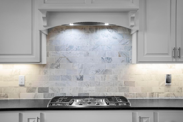 kitchen featuring dark countertops, tasteful backsplash, stainless steel gas stovetop, and white cabinetry