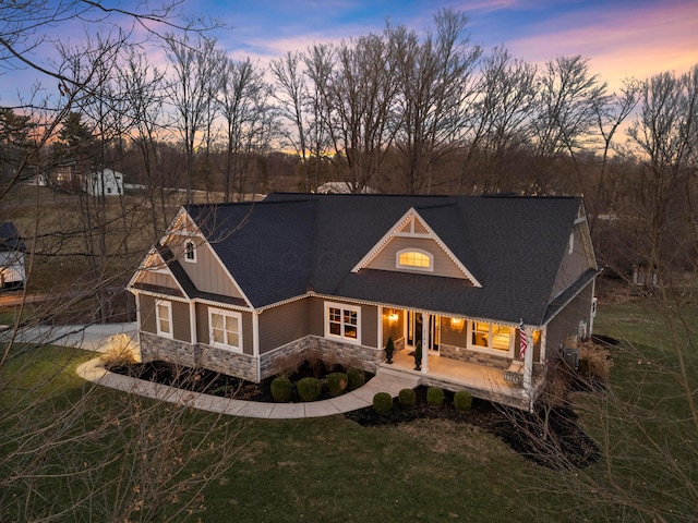 view of front facade with board and batten siding, a front yard, stone siding, and a porch