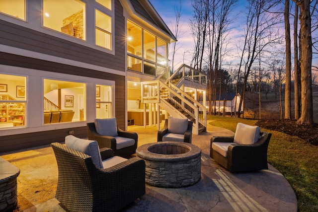 patio terrace at dusk featuring an outdoor fire pit and stairs