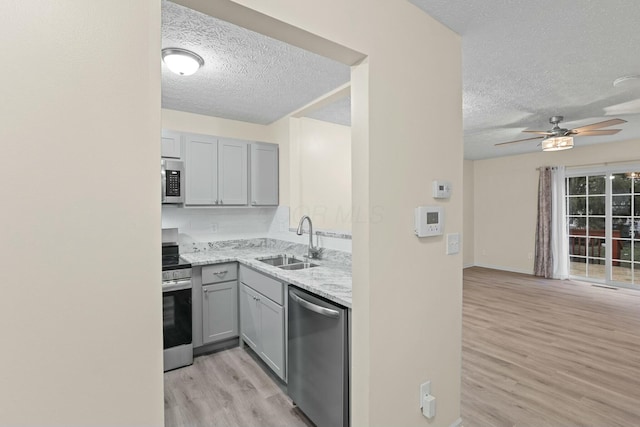 kitchen with light stone counters, appliances with stainless steel finishes, gray cabinets, and sink