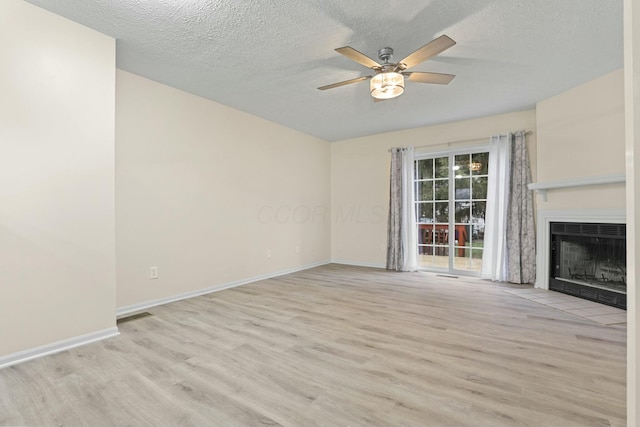 unfurnished living room with ceiling fan, light hardwood / wood-style floors, and a textured ceiling