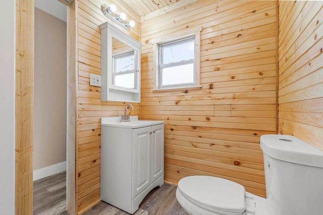 bathroom featuring wood-type flooring, vanity, wood walls, and toilet