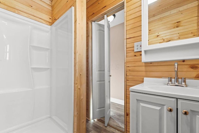 bathroom featuring hardwood / wood-style floors, wooden walls, and vanity