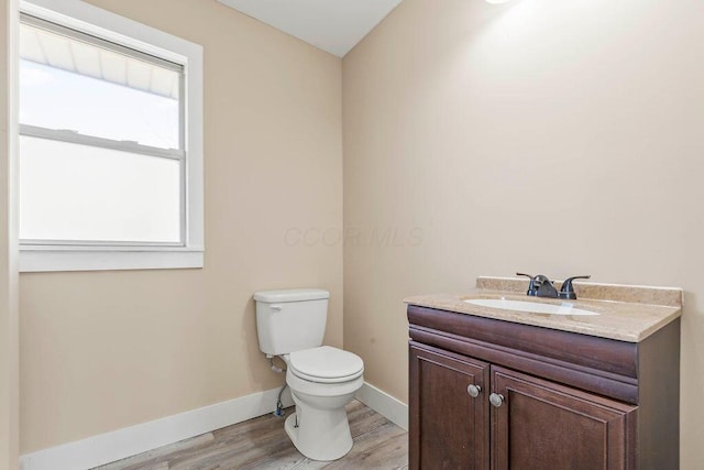 bathroom featuring toilet, vanity, and hardwood / wood-style floors