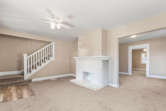 unfurnished living room with a brick fireplace, ceiling fan, and carpet flooring