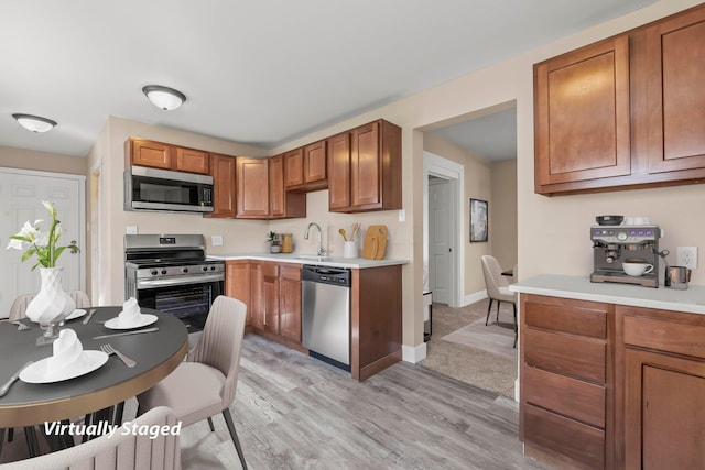 kitchen with sink, appliances with stainless steel finishes, and light hardwood / wood-style flooring