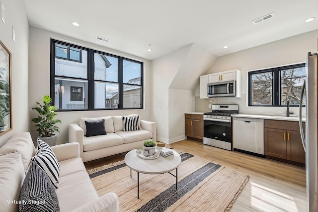 living area featuring recessed lighting, visible vents, and light wood finished floors