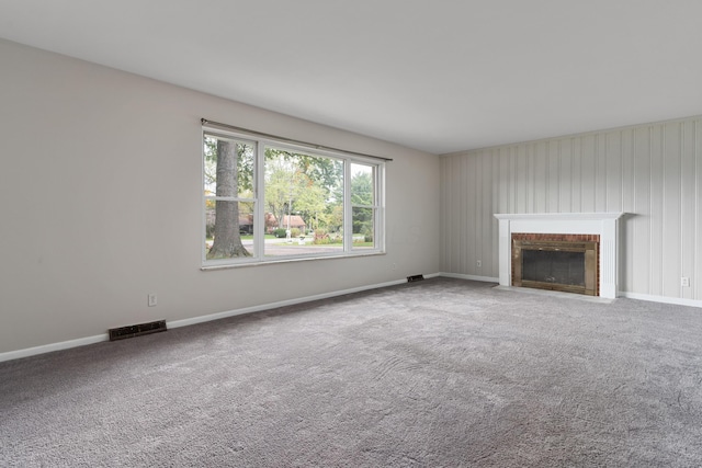 unfurnished living room with carpet flooring and a brick fireplace