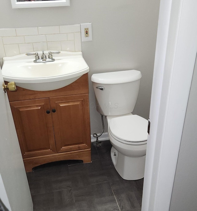 bathroom featuring vanity, decorative backsplash, and toilet