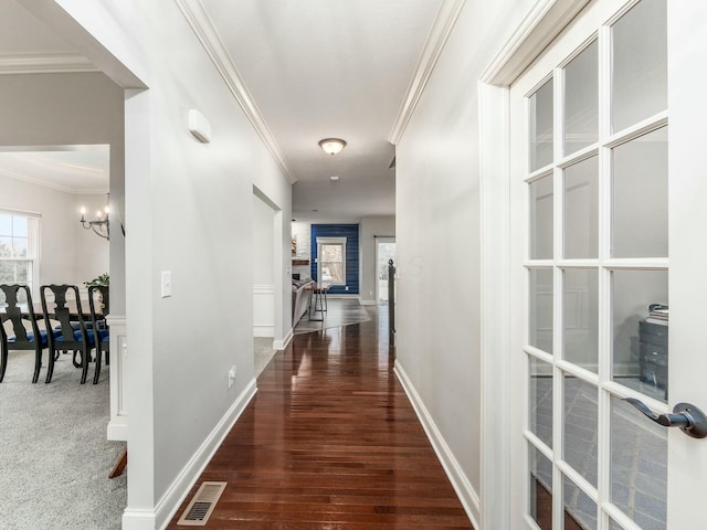 hall featuring ornamental molding, dark wood-type flooring, and a chandelier