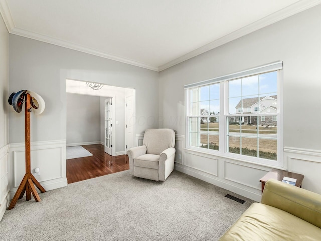 sitting room featuring ornamental molding and dark carpet