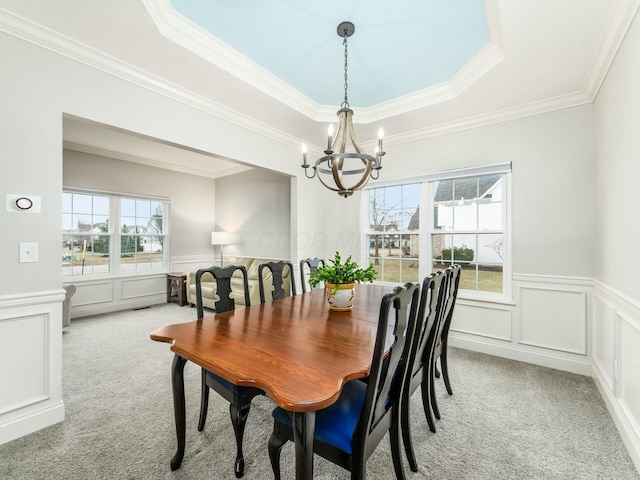 carpeted dining space featuring an inviting chandelier and a tray ceiling