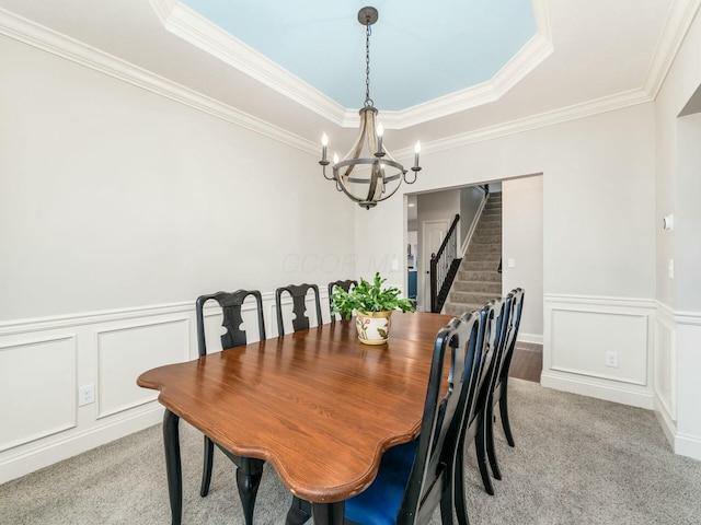 dining area with a notable chandelier, crown molding, light colored carpet, and a raised ceiling