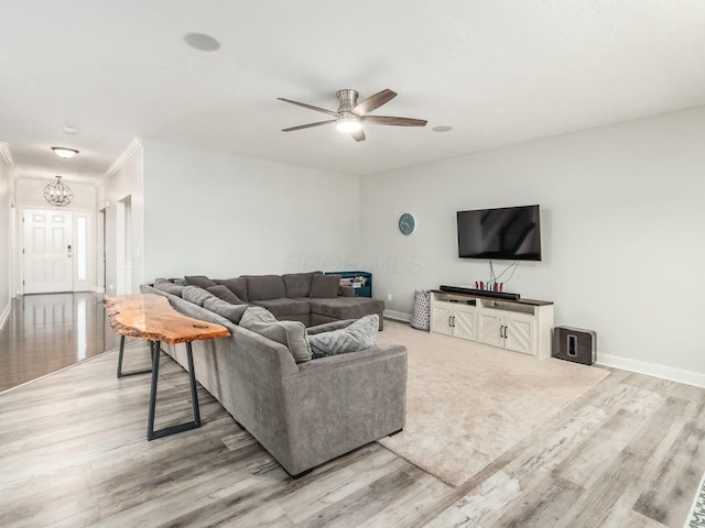 living room featuring ceiling fan with notable chandelier and light hardwood / wood-style flooring