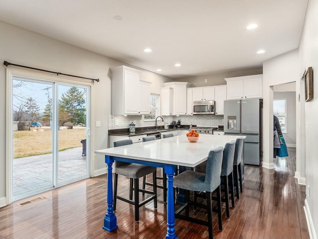 kitchen with a breakfast bar area, white cabinetry, a center island, stainless steel appliances, and backsplash