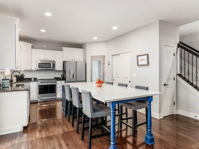 kitchen featuring sink, a breakfast bar, appliances with stainless steel finishes, white cabinets, and a kitchen island