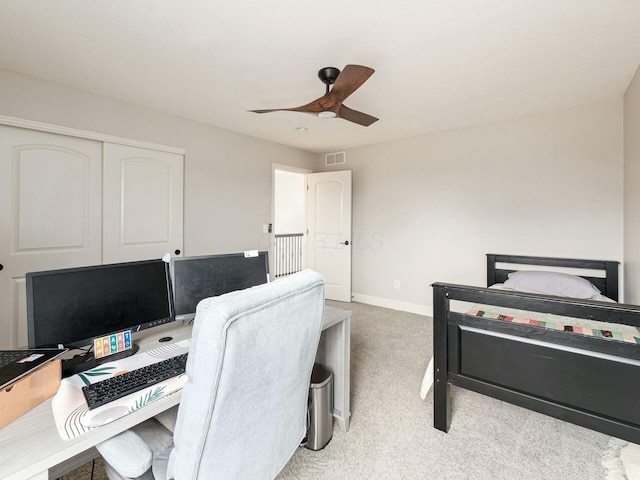 bedroom with light colored carpet, ceiling fan, and a closet