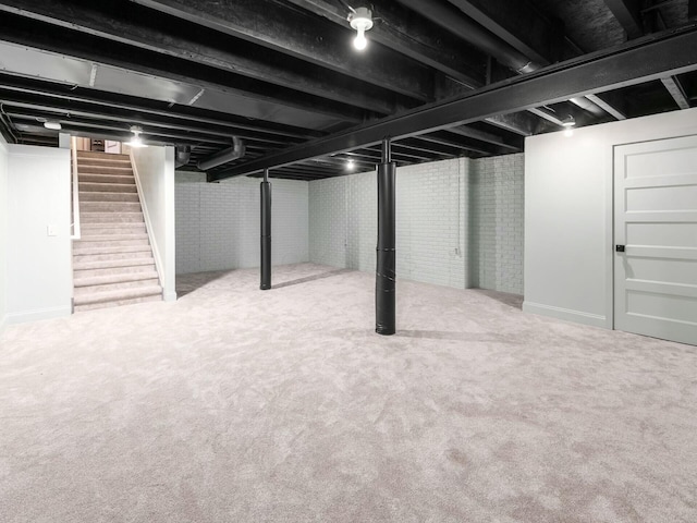 basement featuring brick wall and carpet flooring