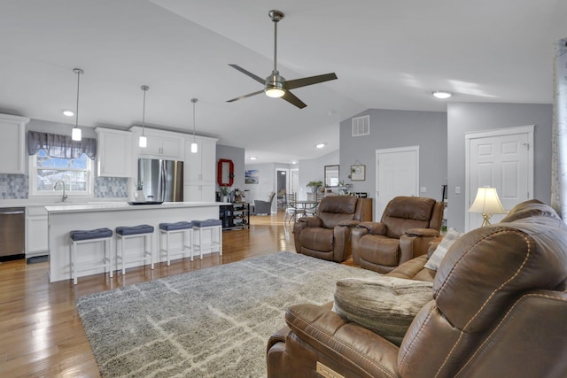 living room featuring hardwood / wood-style floors, vaulted ceiling, and ceiling fan