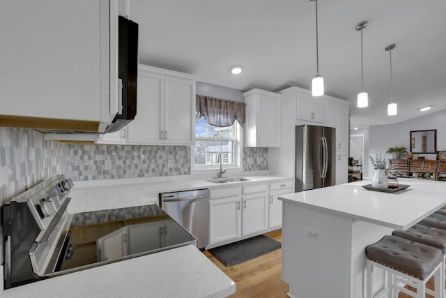 kitchen featuring white cabinetry, stainless steel appliances, a kitchen bar, and sink