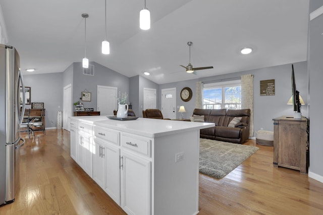 kitchen featuring stainless steel fridge, light hardwood / wood-style flooring, white cabinetry, a center island, and decorative light fixtures