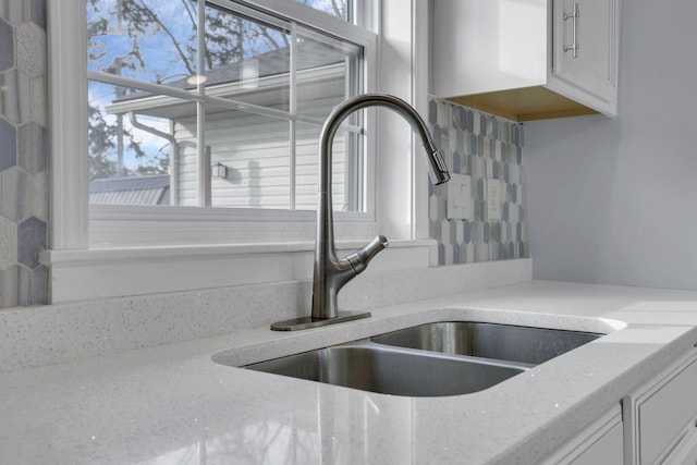 details with light stone counters, sink, and white cabinets