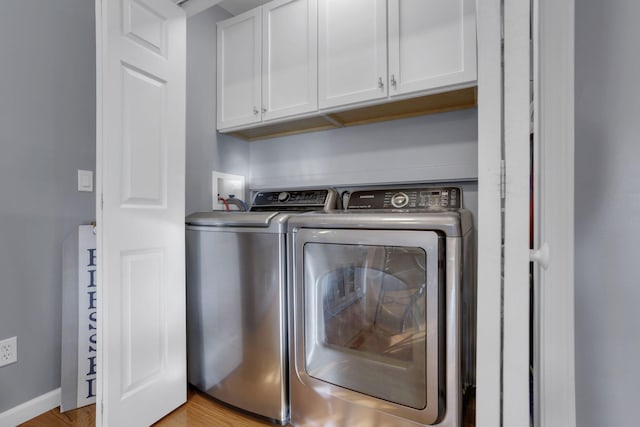 laundry area featuring cabinets, separate washer and dryer, and light hardwood / wood-style flooring