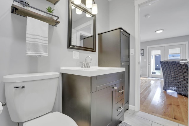 bathroom featuring french doors, vanity, hardwood / wood-style flooring, and toilet