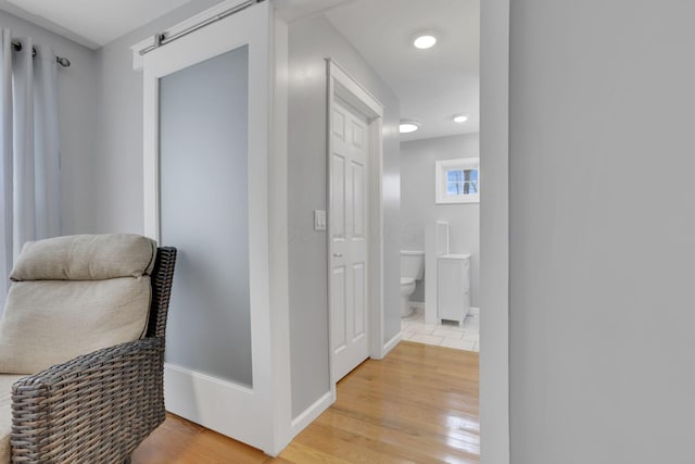 corridor featuring a barn door and light wood-type flooring