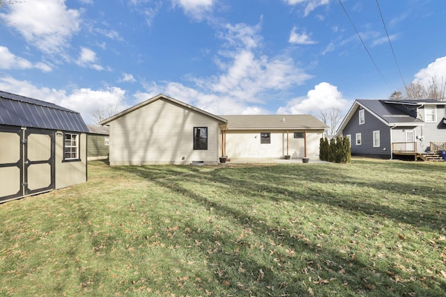 back of property with a storage unit and a yard