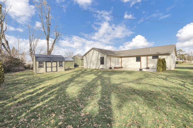 rear view of property featuring a storage shed, a lawn, and a patio area