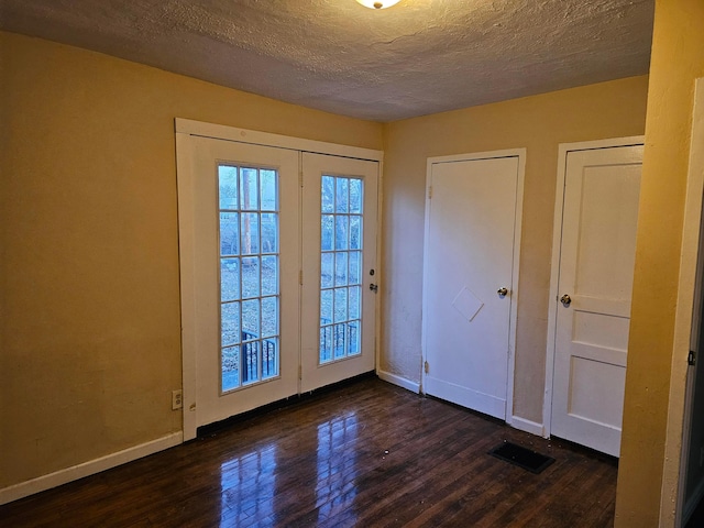 doorway with dark hardwood / wood-style flooring and a textured ceiling