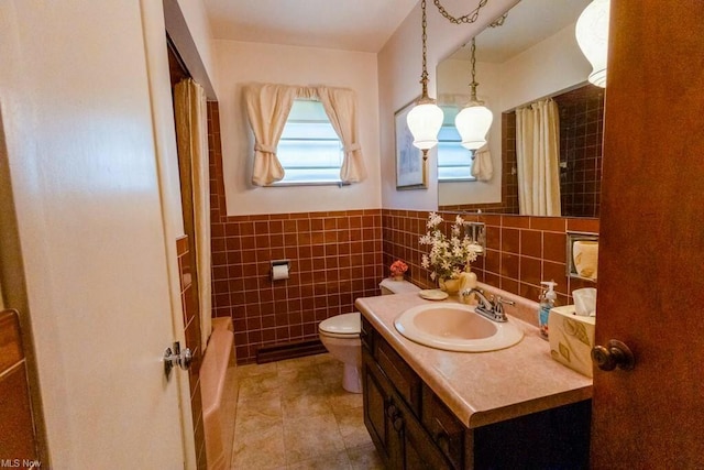 full bathroom with tile patterned floors, toilet, tile walls, vanity, and shower / bath combo with shower curtain