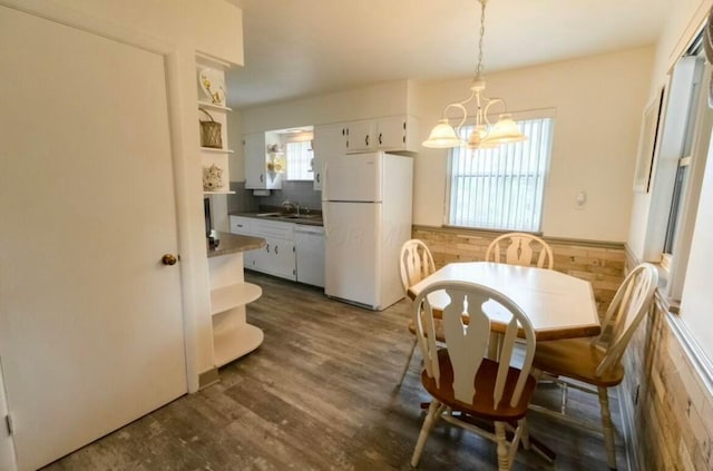 dining space featuring an inviting chandelier, sink, and dark wood-type flooring