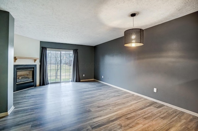 unfurnished living room with wood-type flooring and a textured ceiling