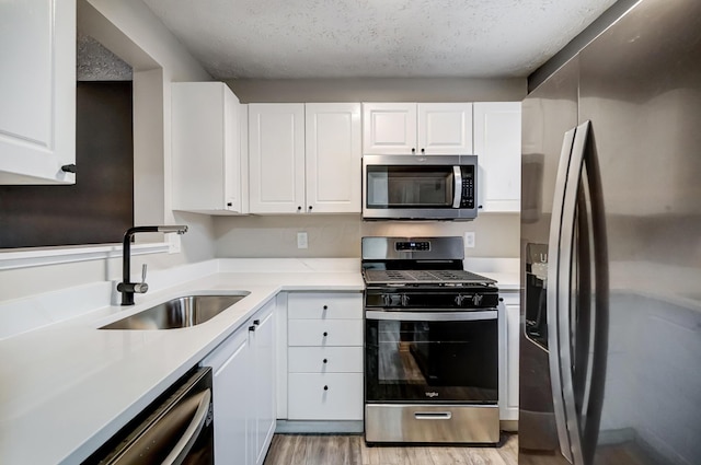 kitchen with white cabinetry, appliances with stainless steel finishes, sink, and a textured ceiling