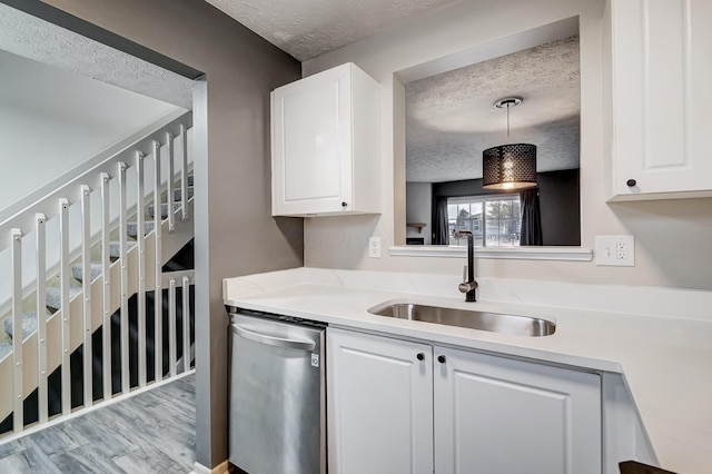 kitchen with white cabinetry, stainless steel dishwasher, sink, and pendant lighting