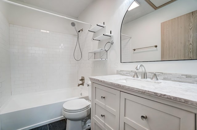 full bathroom featuring vanity, tiled shower / bath, and toilet