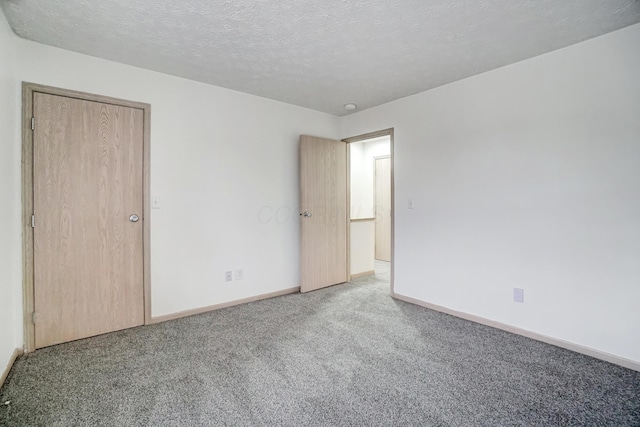 empty room with carpet floors and a textured ceiling