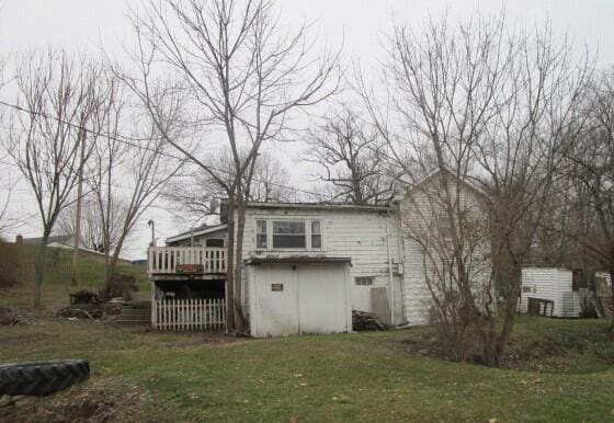 rear view of house featuring a wooden deck and a yard