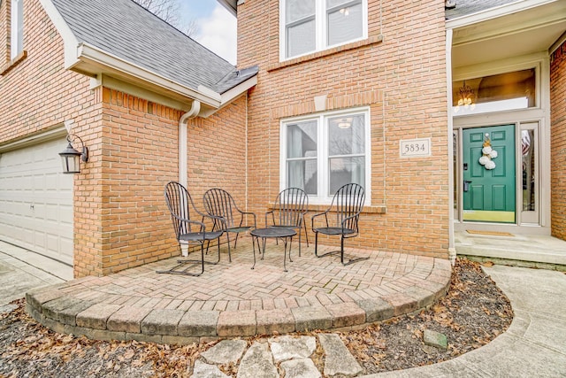 view of exterior entry with a garage and a patio