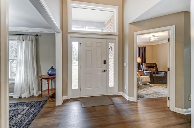 foyer with ornamental molding and dark hardwood / wood-style floors