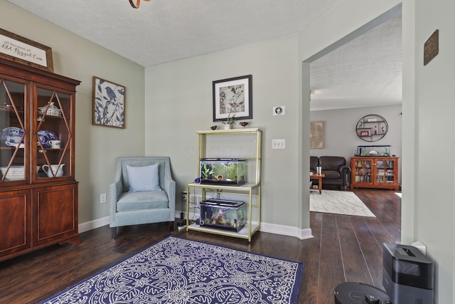 living area featuring a textured ceiling, wood finished floors, and baseboards