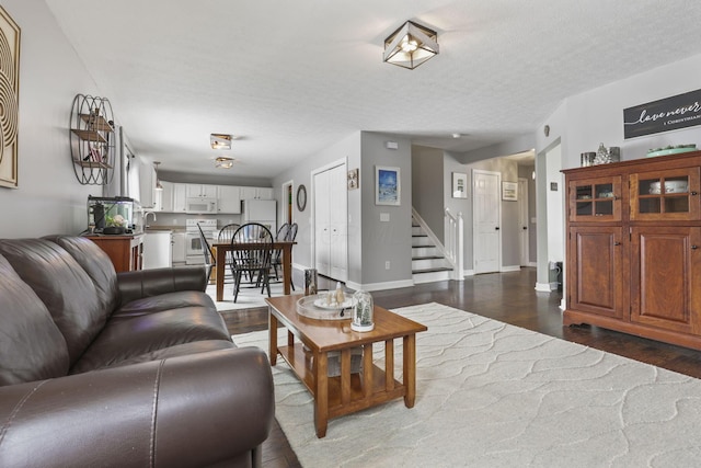 living room with a textured ceiling, stairway, wood finished floors, and baseboards