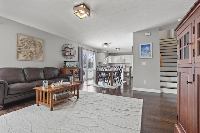 living room featuring dark wood-style flooring, baseboards, stairway, and a textured ceiling